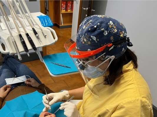 igienista dentale mentre lavora con un paziente alla poltrona